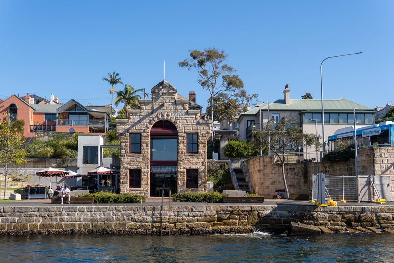 The old sandstone boat store on the Balmain East waterfront, with houses on the slope behind