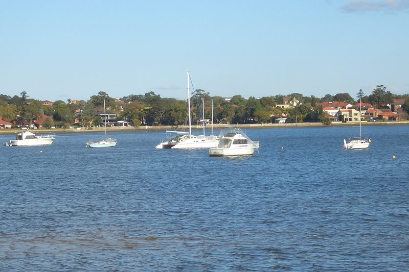 Boats moored on Canada Bay with the foreshore houses beyond
