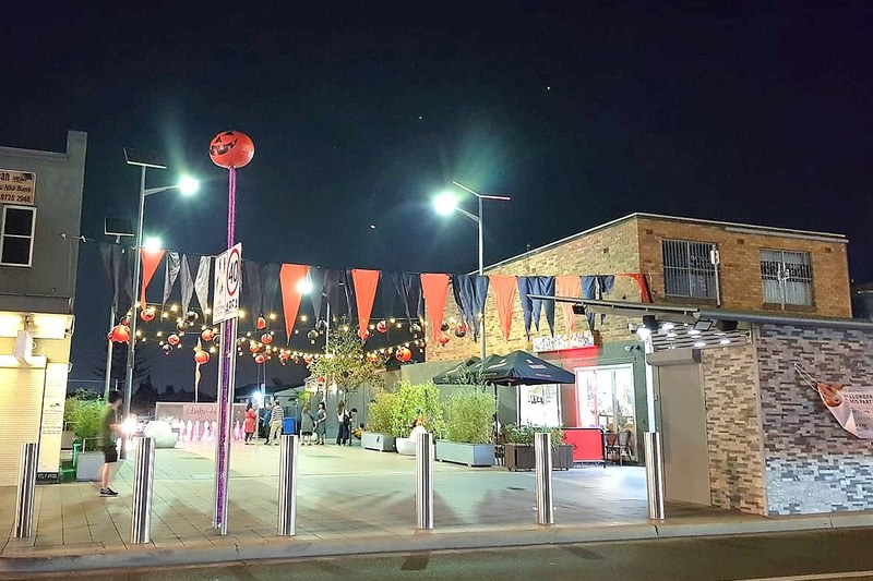 Canley Heights town square at night, with bunting and lights above the restaurant strip