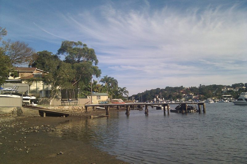 Waterfront houses and a timber jetty at Caringbah South at low tide