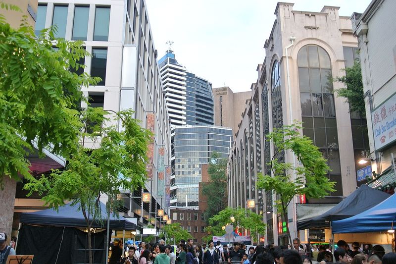 Dixon Street in Chinatown at dusk, with apartment towers rising above the shopfronts