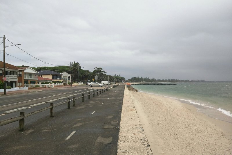The beachfront road and seawall looking along the bay at Dolls Point