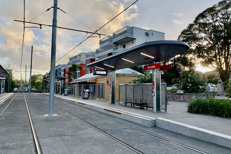 Dundas light rail stop at dusk, with apartments and the old station building behind