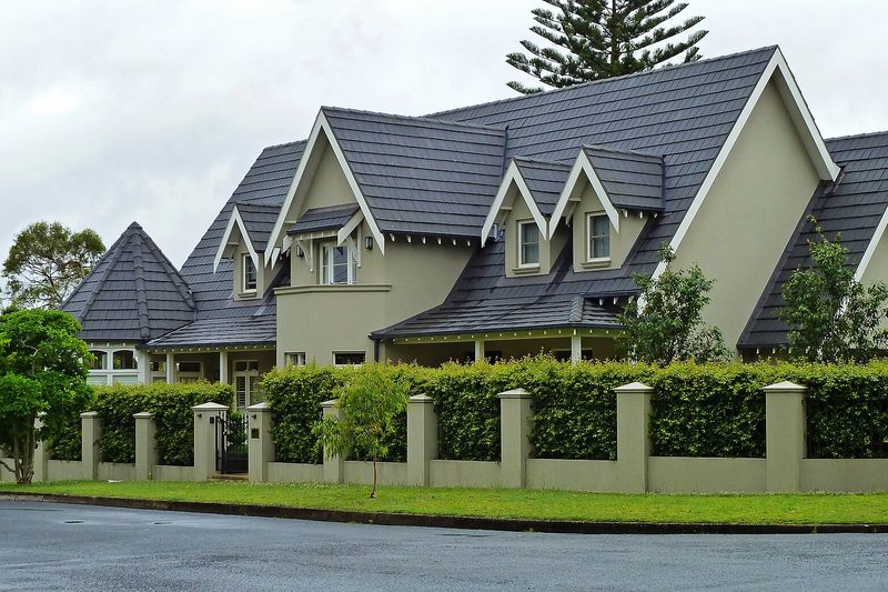 A large gabled house behind a clipped hedge on a street in East Killara