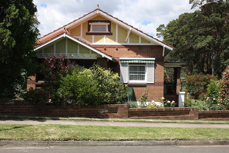 A brick Californian bungalow behind a low brick wall and garden, Epping