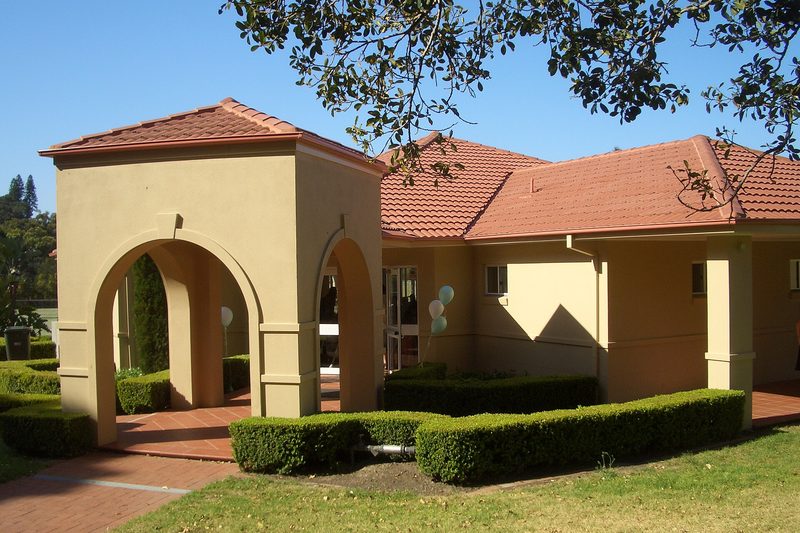A rendered house with terracotta roof tiles and an arched entrance in Huntleys Cove