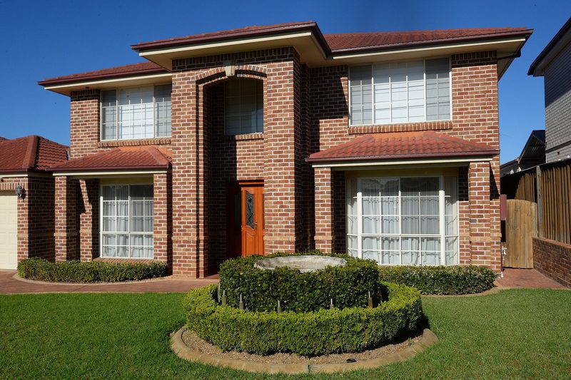 A two storey brick home with a clipped hedge and lawn in Kellyville Ridge