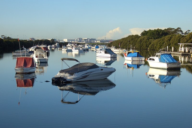 Small boats moored on the still water at Kyeemagh, with the airport beyond