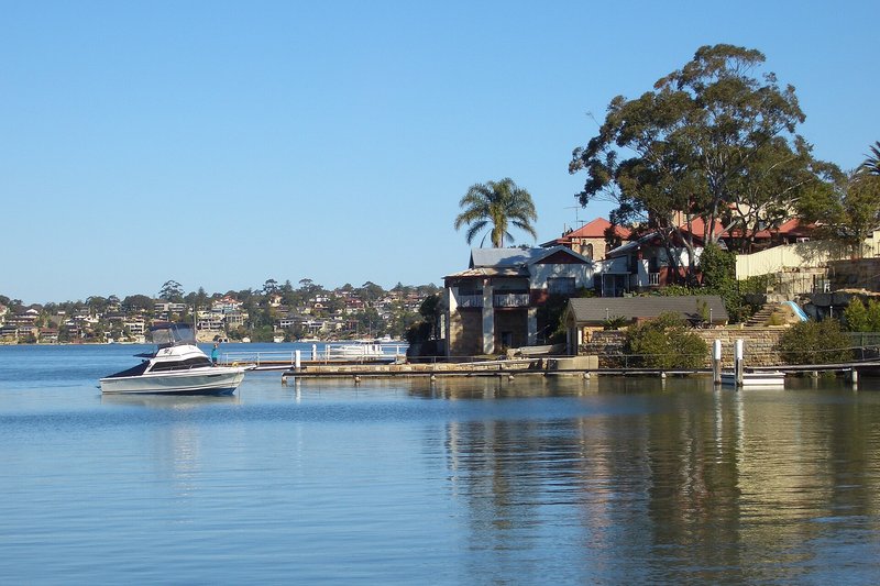A cruiser at anchor off the sandstone boatsheds and homes at Kyle Bay