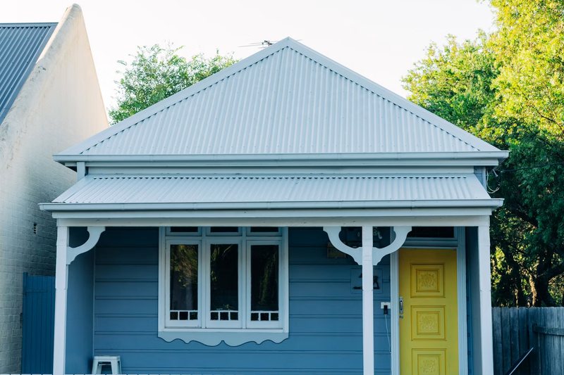 A weatherboard cottage with a yellow front door on a Leichhardt street