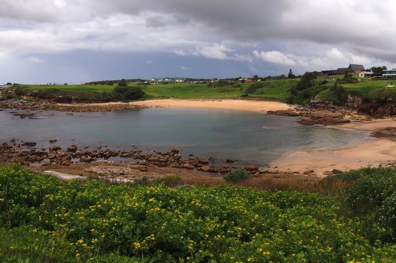 The sandy curve of Little Bay, seen from the headland