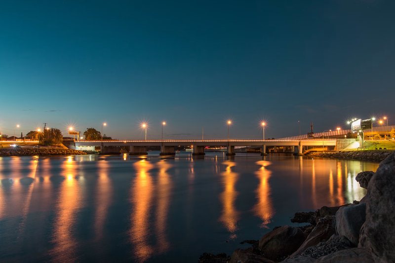 Bridge lights reflected on the water at dusk near Mascot