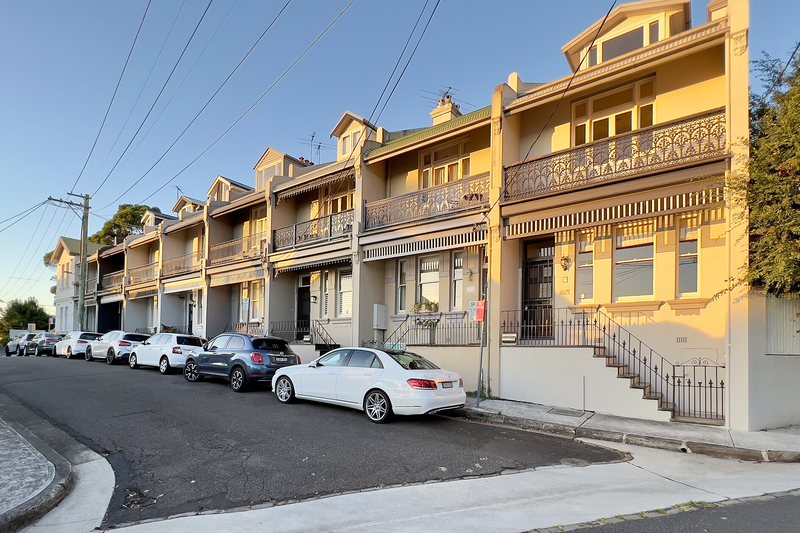 A row of Victorian terraces with iron lacework balconies on a McMahons Point street