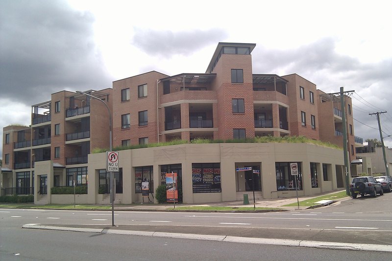 A brick apartment building above shopfronts on Woodville Road, Merrylands