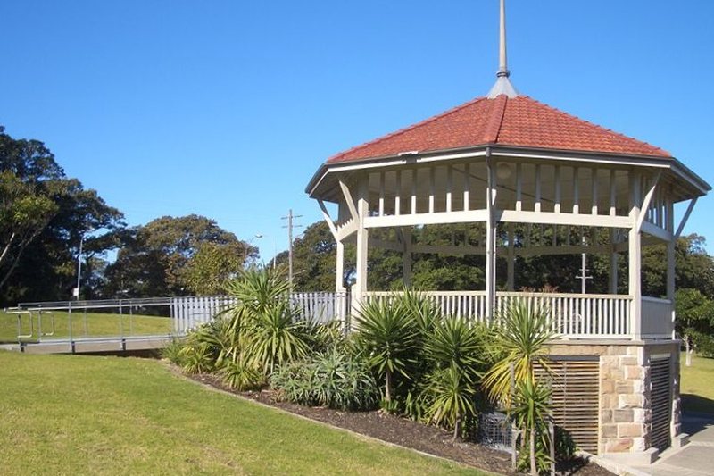 The timber rotunda in Moore Park, with lawn and fig trees behind