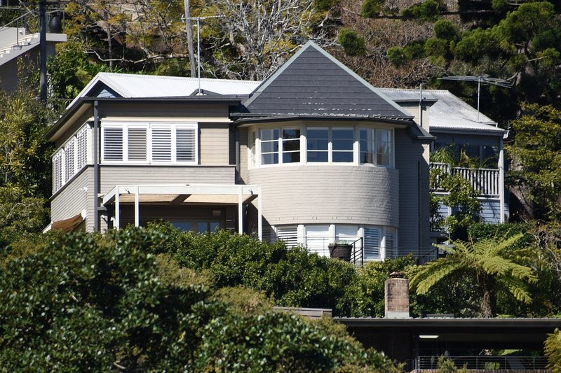 A weatherboard and brick house on the wooded slope above Mosman Bay