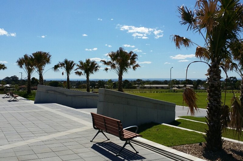 Paved terrace, benches and palms at the canal park in Potts Hill