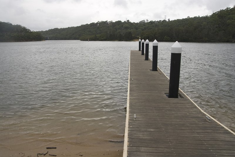 A timber jetty reaching out into the Georges River at Revesby Heights under an overcast sky