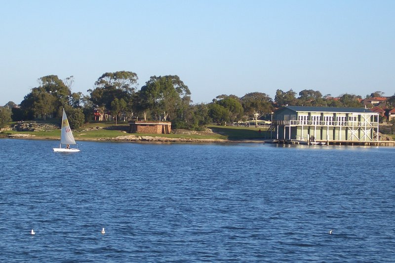 The sailing club and parkland at Rodd Point on Iron Cove, with a dinghy on the water