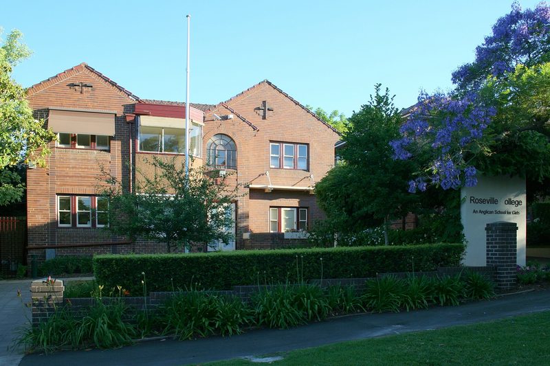 Brick school buildings and a jacaranda in flower at Roseville