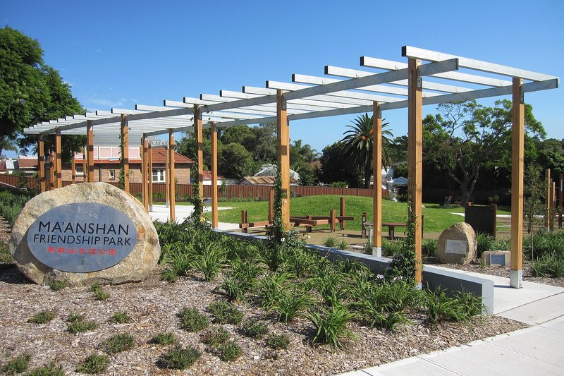 The pergola and lawn at Friendship Park, with houses along the far side, South Hurstville