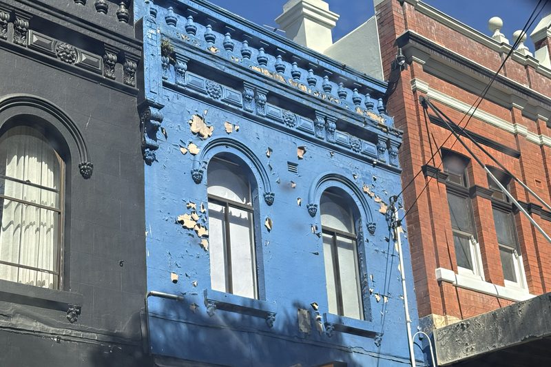 A Victorian shopfront facade with weathered blue paint and cast cement detail in Surry Hills