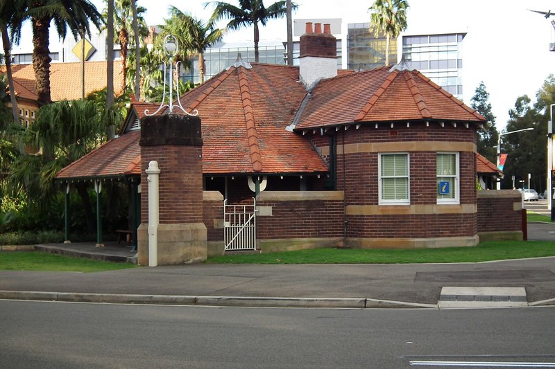 The former abattoir gatehouse in the heritage precinct at Sydney Olympic Park, with towers behind