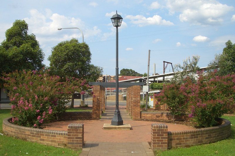 Portico Park at Toongabbie, a brick paved square with crepe myrtles beside the station