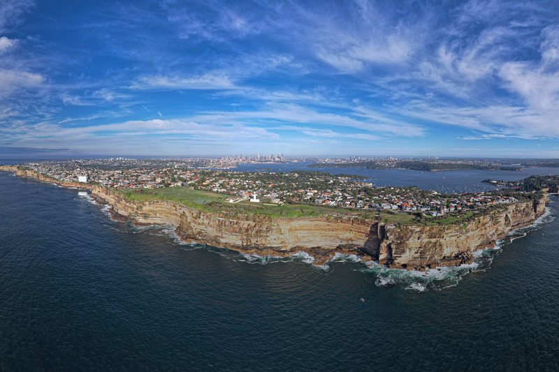 Aerial view of the Vaucluse clifftops, with Macquarie Lighthouse on the headland and the city beyond