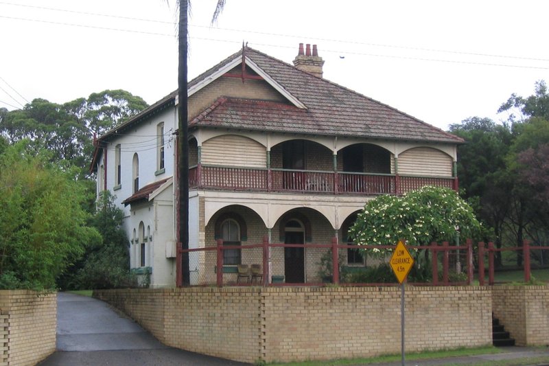 A two storey house with verandahs behind a brick wall on Victoria Road, West Ryde