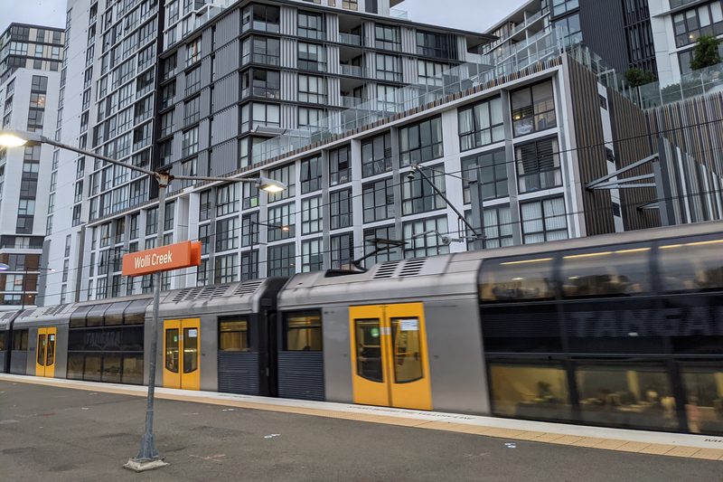 A train at Wolli Creek station, with the suburb's high-rise apartments behind