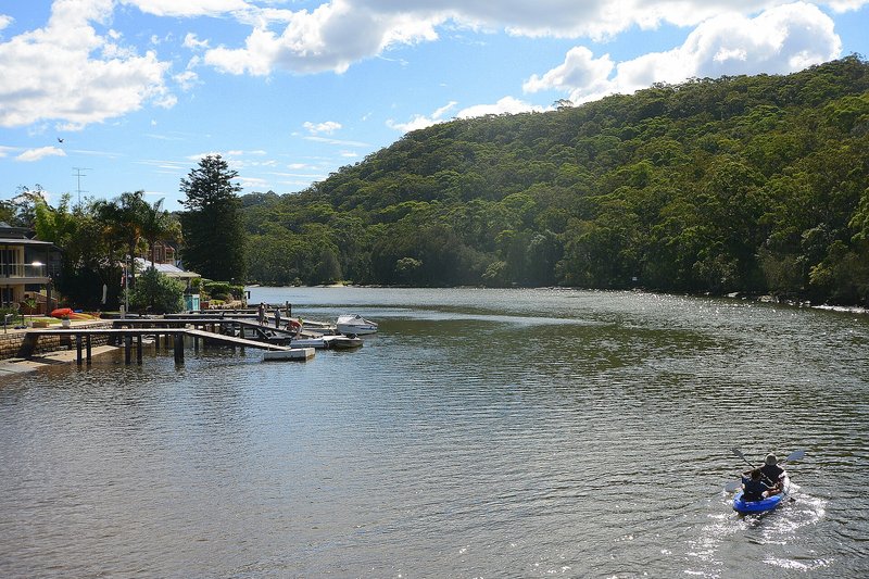 Jetties and houses along the Woronora River below the wooded valley slope